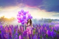 A young girl in a  pink ball gown with balloons in her hands among purple and pink lupines Royalty Free Stock Photo