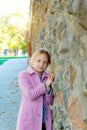 A young girl in a pink coat is leaning against a wall, rubbing in close up. Royalty Free Stock Photo