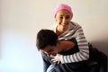 Young girl with pink handkerchief on her head on top of her husband. Concept of breast cancer patients
