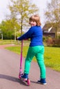 Young girl with pink push scooter looking back Royalty Free Stock Photo