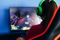 A young girl playing a computer game on professional armchair against monitor in green headphones, live stream, esports Royalty Free Stock Photo