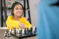 A young girl is playing a game of chess with an adult