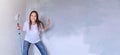 Young girl playing, jumping and aping with paint roller for painting wall.