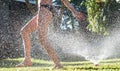 Young girl playing jumping in a garden water lawn sprinkler Royalty Free Stock Photo