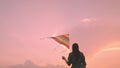 young girl playing with a kite against the backdrop of a pink sunset in sky, women's dream of free life, travel with Royalty Free Stock Photo