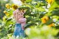 Young girl playing with large yellow sunflowers on her familys farm