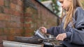 A young girl playing with a mud outdoor kitchen holding a teapot