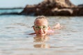 Young girl playing, swiming and splashing in fresh sea water. Smilling blonde girl in swimsuit with and swimming goggles Royalty Free Stock Photo