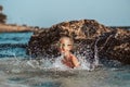 Young girl playing, swiming and splashing in fresh sea water. Smilling blonde girl in swimsuit with and swimming goggles Royalty Free Stock Photo