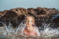 Young girl playing, swiming and splashing in fresh sea water. Smilling blonde girl in swimsuit with and swimming goggles Royalty Free Stock Photo