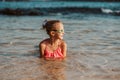 Young girl playing, swiming and splashing in fresh sea water. Smilling blonde girl in swimsuit with and swimming goggles Royalty Free Stock Photo