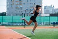 Young girl playing tennis on a new court, jumping while striking ball Royalty Free Stock Photo