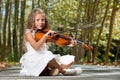 Young girl playing violin in the woods. Royalty Free Stock Photo