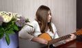 A young girl plays guitar sitting on the floor of her home. Home insulation and musical creativity Royalty Free Stock Photo