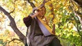 A young girl plays the harp. She sits under a tree in the autumn Park.