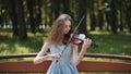 A young girl plays the violin in the city park. Royalty Free Stock Photo