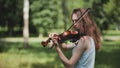 A young girl plays the violin in the city park. Royalty Free Stock Photo