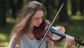 A young girl plays the violin in the city park. Royalty Free Stock Photo