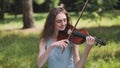 A young girl plays the violin in the city park. Royalty Free Stock Photo