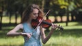 A young girl plays the violin in the city park. Royalty Free Stock Photo