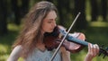 A young girl plays the violin in the city park. Royalty Free Stock Photo