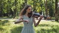 A young girl plays the violin in the city park. Royalty Free Stock Photo