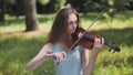 A young girl plays the violin in the city park. Royalty Free Stock Photo