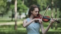 A young girl plays the violin in the city park. Royalty Free Stock Photo