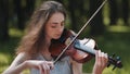 A young girl plays the violin in the city park. Royalty Free Stock Photo