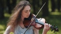 A young girl plays the violin in the city park. Royalty Free Stock Photo