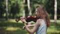 A young girl plays the violin in the city park. Royalty Free Stock Photo