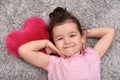 Young girl with plush red heart lying on the carpet Royalty Free Stock Photo