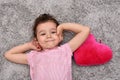 Young girl with plush red heart lying on the carpet Royalty Free Stock Photo