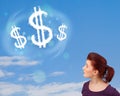 Young girl pointing at dollar sign clouds on blue sky Royalty Free Stock Photo