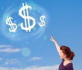 Young girl pointing at dollar sign clouds on blue sky Royalty Free Stock Photo