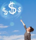 Young girl pointing at dollar sign clouds on blue sky Royalty Free Stock Photo