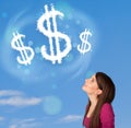 Young girl pointing at dollar sign clouds on blue sky Royalty Free Stock Photo