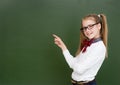 Young girl points on empty green chalkboard