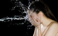 Young girl portrait and splash water in her face. beautiful female model on black background. Royalty Free Stock Photo