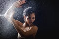 Young girl portrait and splashing water in her face. beautiful female model on black background. Royalty Free Stock Photo