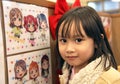YOUNG GIRL POSES BESIDE ANIME PICTURE