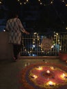 A young girl standing besides a brightly lit Rangoli during Diwali