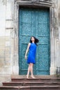 Young girl posing in a blue dress for the camera on a background of green metal door. Confident stylish woman looks to the side Royalty Free Stock Photo