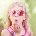 Young girl posing in fancy pink pentagonal shaped sunglasses outdoor. Cute adorable stylish Caucasian child with long blonde hair