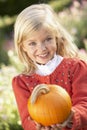 Young girl posing with pumpkin in garden Royalty Free Stock Photo