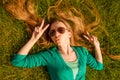 Young Girl Pouting And Gesturing With Two Fingers While Lying On Grass