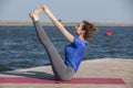 Young girl practices yoga on the shore of the lake, the concept of enjoying privacy and concentration, sunlight