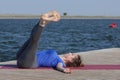 Young girl practices yoga on the shore of the lake, the concept of enjoying privacy and concentration, sunlight