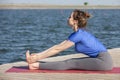 Young girl practices yoga on the shore of the lake, the concept of enjoying privacy and concentration, sunlight