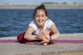 Young girl practices yoga on the shore of the lake, the concept of enjoying privacy and concentration, sunlight